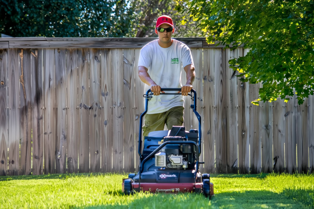wichita lawn pros landscaper mowing lawn with a push mower